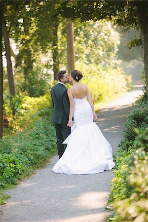 simsearch:700-05786584,k - Backview of Bride and Groom kissing and holding hands, walking down pathway outdoors, on Wedding Day Photographie de stock - Rights-Managed, Code: 700-06939704