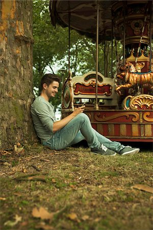 simsearch:600-07110828,k - Young Man using Cell Phone while Sitting near Carousel, Mannheim, Baden-Wurttemberg, Germany Stock Photo - Rights-Managed, Code: 700-06962073