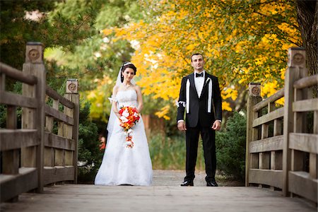 simsearch:700-07199878,k - Portrait of bride and groom standing on bridge in public garden, in Autumn, looking at camera, Ontario, Canada Stock Photo - Rights-Managed, Code: 700-07199859