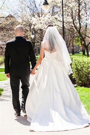 Backview of bride in wedding gown with bridegroom, holding hands and walking down pathway in park in Spring on Wedding Day, Canada Stock Photo - Rights-Managed, Code: 700-07237612
