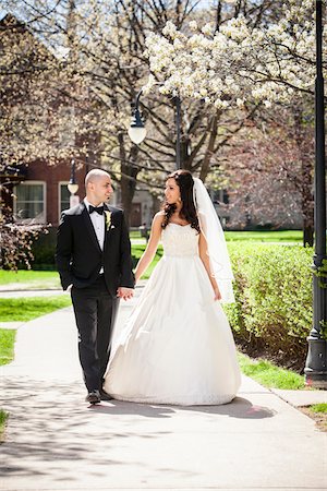 simsearch:700-07199878,k - Bride in wedding gown with bridegroom in tuxedo, looking at each other and holding hands, walking down pathway in park in Spring on Wedding Day, Canada Stock Photo - Rights-Managed, Code: 700-07237613