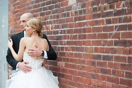 simsearch:700-07199878,k - Portrait of Bride and Groom standing in front of brick wall, embracing outdoors on Wedding Day, Canada Stock Photo - Rights-Managed, Code: 700-07232348