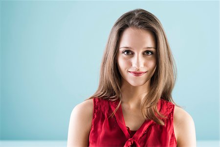 Close-up portrait of teenage girl looking at camera and smiling, studio shot on blue background Foto de stock - Con derechos protegidos, Código: 700-07567427