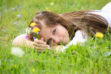 simsearch:700-08080570,k - Close-up of a young woman lying in a flower meadow in summer, holding a small bouquet of wildflowers, Upper Palatinate, Bavaaria, Germany Stock Photo - Rights-Managed, Code: 700-07760188