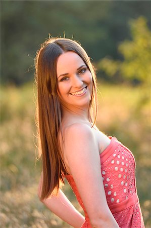 simsearch:700-06939632,k - Portrait of young woman standing in a meadow at sunset in early autumn, looking at camera and smiling, Bavaria, Germany Stock Photo - Rights-Managed, Code: 700-07760228