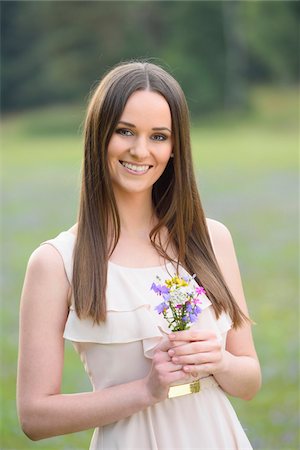 simsearch:700-06939632,k - Portrait of young woman holding a bouquet of flowers, standing in a meadow at sunset in early autumn, looking at camera and smiling, Bavaria, Germany Stock Photo - Rights-Managed, Code: 700-07760233