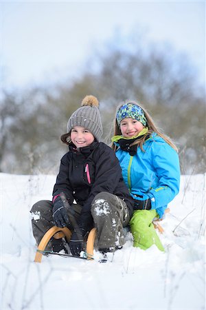 rolling (action) - Portrait of two girls playing in the snow with sled, winter, Bavaria, Germany Stock Photo - Rights-Managed, Code: 700-07991772