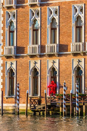 simsearch:862-05998030,k - Person standing in doorway of sunlit historical buildings wearing red Carnevale costume along the Grand Canal in Venice, Italy Stock Photo - Rights-Managed, Code: 700-08986655