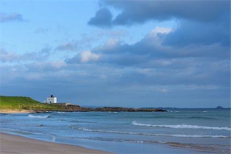 Beach along the North Sea in Bamburgh with the Bamburgh Lighthouse in the distance in Northumberland, England, United Kingdom Stock Photo - Rights-Managed, Code: 700-09013955