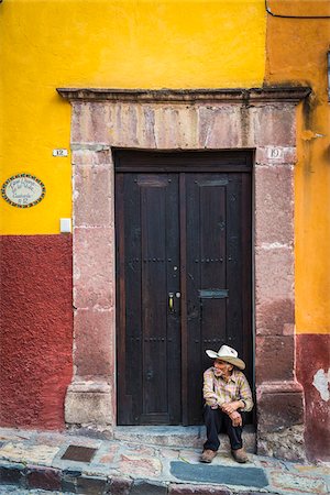 Man sitting on doorstep in front of traditional building in San Miguel de Allende, Mexico Stock Photo - Rights-Managed, Code: 700-09088114