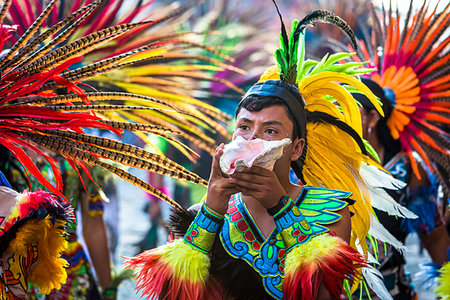 Indigenous tribal dancer wearing colurful feather headdress and blowing into a conch shell at a St Michael Archangel Festival parade in San Miguel de Allende, Mexico Photographie de stock - Rights-Managed, Code: 700-09273278