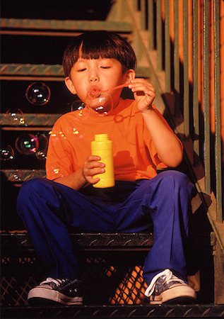 simsearch:632-05604245,k - Boy Sitting on Stairs Blowing Bubbles Stock Photo - Rights-Managed, Code: 700-00025643