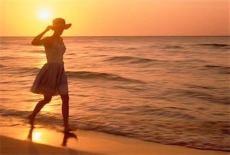Silhouette de femme qui marche sur la plage au coucher du soleil Photographie de stock - Rights-Managed, Code: 700-00028524