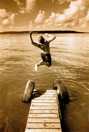 Back View of Boy in Swimwear Jumping into Lake from Dock Stock Photo - Rights-Managed, Code: 700-00032928