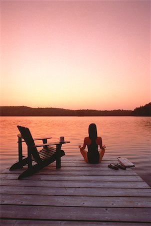 Back View of Woman in Swimwear Sitting on Dock with Adirondack Chair at Sunset Foto de stock - Con derechos protegidos, Código: 700-00053265