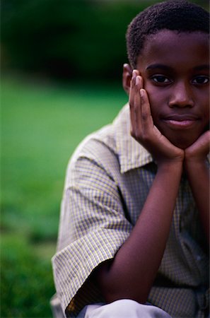 Portrait of Boy Sitting Outdoors Resting Head on Hands Stock Photo - Rights-Managed, Code: 700-00069957