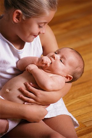 Girl Sitting on Floor, Holding Baby Stock Photo - Rights-Managed, Code: 700-00074997