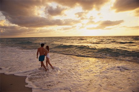 simsearch:700-00021491,k - Couple en maillot de bain, marchant en Surf sur la plage au coucher du soleil Photographie de stock - Rights-Managed, Code: 700-00075482
