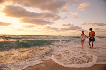 simsearch:700-00021491,k - Couple en maillot de bain, marchant en Surf sur la plage au coucher du soleil Photographie de stock - Rights-Managed, Code: 700-00075483