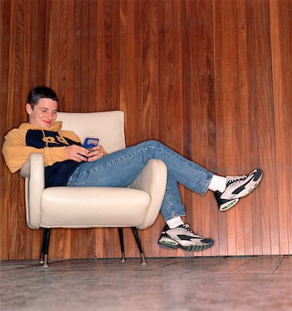 simsearch:6108-06905230,k - Teenage Boy Sitting in Chair Playing Handheld Video Game Stock Photo - Rights-Managed, Code: 700-00071703