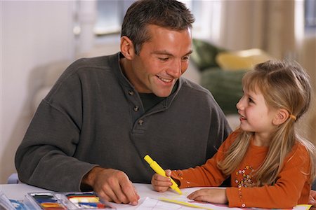 parents sitting with kids for crafts - Father and Daughter Sitting at Table with Coloring Book Stock Photo - Rights-Managed, Code: 700-00073460