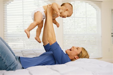 simsearch:700-00080994,k - Mother Lying on Bed, Lifting Baby In Air Stock Photo - Rights-Managed, Code: 700-00084520