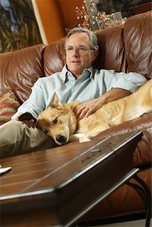 simsearch:700-00983142,k - Homme assis sur un canapé avec chien détenant le contrôle à distance Photographie de stock - Rights-Managed, Code: 700-00152688