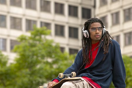 Man Listening to Headphones and Holding Skateboard Foto de stock - Con derechos protegidos, Código: 700-00429839