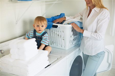 Mother Doing Laundry with Son Sitting on Dryer Stock Photo - Rights-Managed, Code: 700-00476727