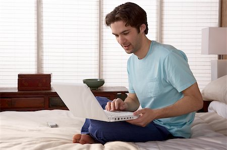 simsearch:700-03058963,k - Man Using Laptop in Bedroom Stock Photo - Rights-Managed, Code: 700-00557356