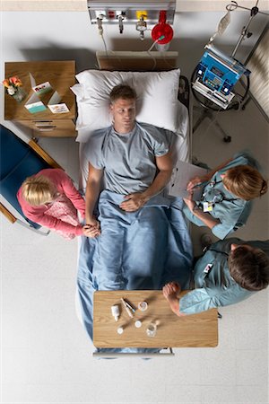 doctor consulting patient in hospital room - People Surrounding Man in Hospital Bed Stock Photo - Rights-Managed, Code: 700-00610972