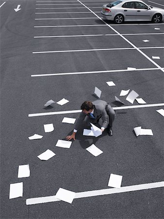 Businessman Picking Up Papers In Parking Lot Stock Photo - Rights-Managed, Code: 700-00644016