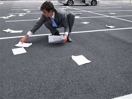 Businessman Picking Up Papers In Parking Lot Stock Photo - Rights-Managed, Code: 700-00644018