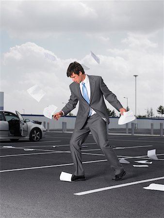 Businessman Trying to Pick Up Papers In Parking Lot Stock Photo - Rights-Managed, Code: 700-00644019