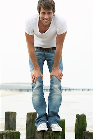 Portrait of Man Standing on Wooden Posts on Beach Stock Photo - Rights-Managed, Code: 700-01082852