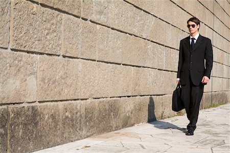 simsearch:700-06701841,k - Businessman walking by Brick Wall with Briefcase Stock Photo - Rights-Managed, Code: 700-01378444