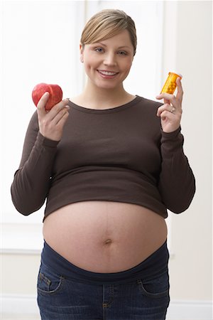 female belly expansion - Pregnant Woman Holding Pills and an Apple Stock Photo - Rights-Managed, Code: 700-01837445