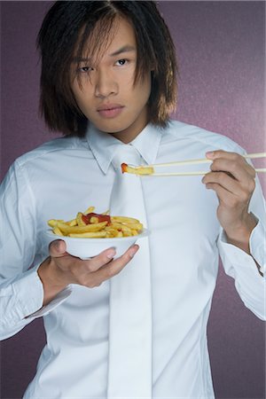 Portrait of Man Eating French Fries With Chopsticks Stock Photo - Rights-Managed, Code: 700-02637564