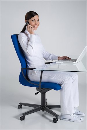 simsearch:700-03058963,k - Portrait of Woman Sitting at a Desk in an Ergonomic Chair, Using Laptop Computer and Talking on Cell Phone Stock Photo - Rights-Managed, Code: 700-02693772