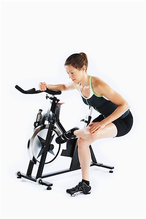 pictures of female athletes bending over - Woman Stretching by Stationary Bicycle Stock Photo - Rights-Managed, Code: 700-03004426