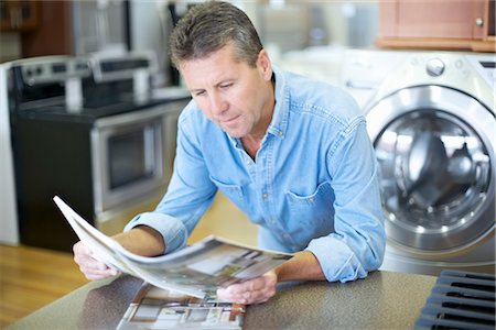 flyer - Man in Appliance Store Reading Brochures Foto de stock - Con derechos protegidos, Código: 700-03178530