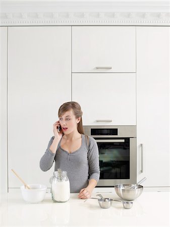 Woman on Cell Phone while Baking Stock Photo - Rights-Managed, Code: 700-03451391