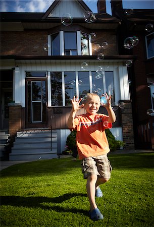 Boy Chasing Bubbles on Front Lawn, Toronto, Ontario, Canada Stock Photo - Rights-Managed, Code: 700-03520600