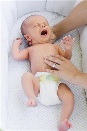 Mains de la mère tenant un bébé dans le lit d'enfant Photographie de stock - Rights-Managed, Code: 700-03644519