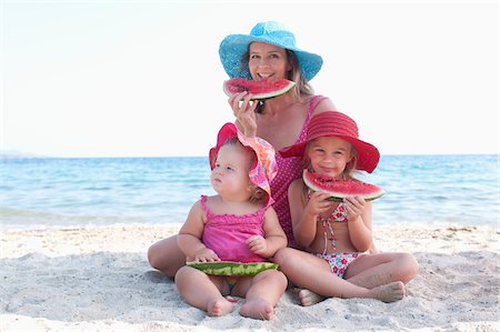 Mother with Daughers Eating Watermelon on Beach Foto de stock - Con derechos protegidos, Código: 700-03739268