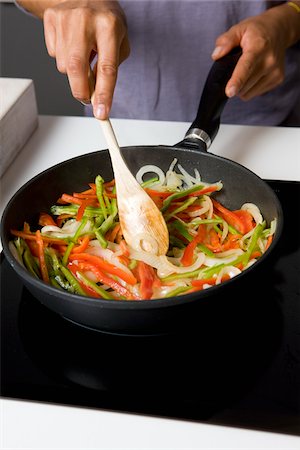 Cooking the peppers and the onions in a frying pan Stock Photo - Rights-Managed, Code: 825-06049448