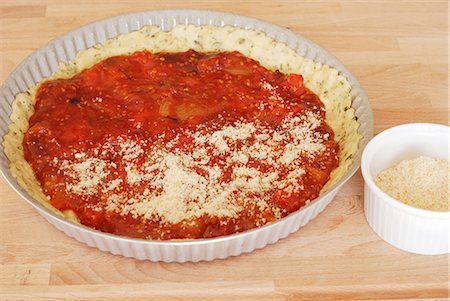 simsearch:825-05814612,k - Spreading the pureed tomatoes on the shortbread pastry in the mould and sprinkle with parmesan Stock Photo - Rights-Managed, Code: 825-07076877