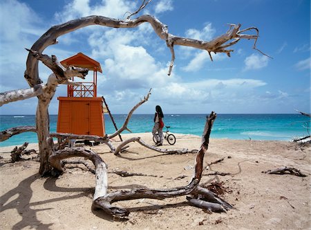 Man walking along beach with bicycle near driftwood and lifeguard hut Stock Photo - Rights-Managed, Code: 832-03724182