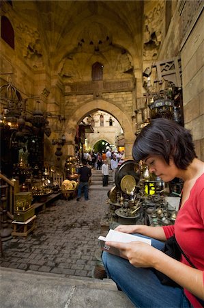 egypt - Woman reading guidebook beside stalls in covered gateway in Khan El Khalili Stock Photo - Rights-Managed, Code: 832-03724717