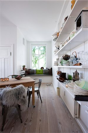 Open plan kitchen with wall shelving and window seat. Stock Photo - Rights-Managed, Code: 845-07561470